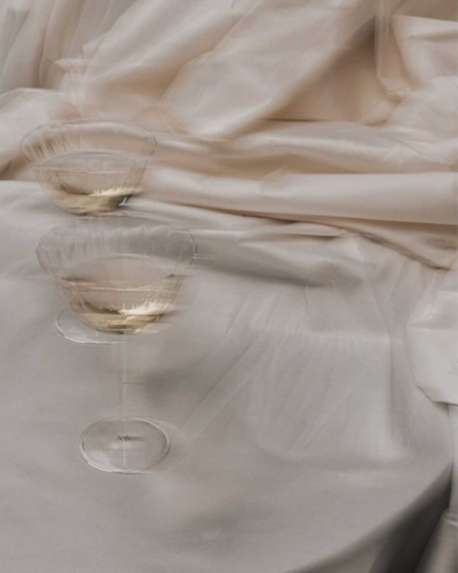 Champagne coupes on ivory drapery