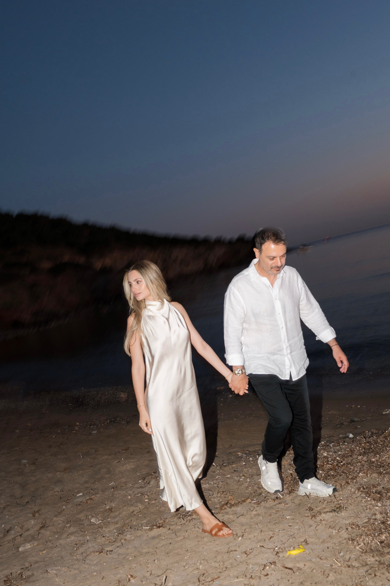 Takis and Xenia walking on the beach at twilight